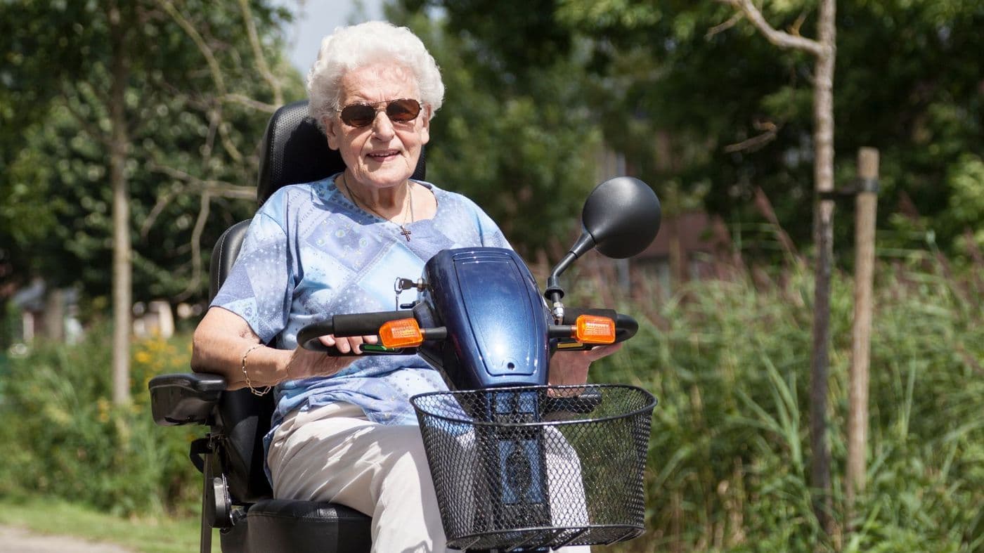 A smiling customer sitting on a mobility scooter outdoors