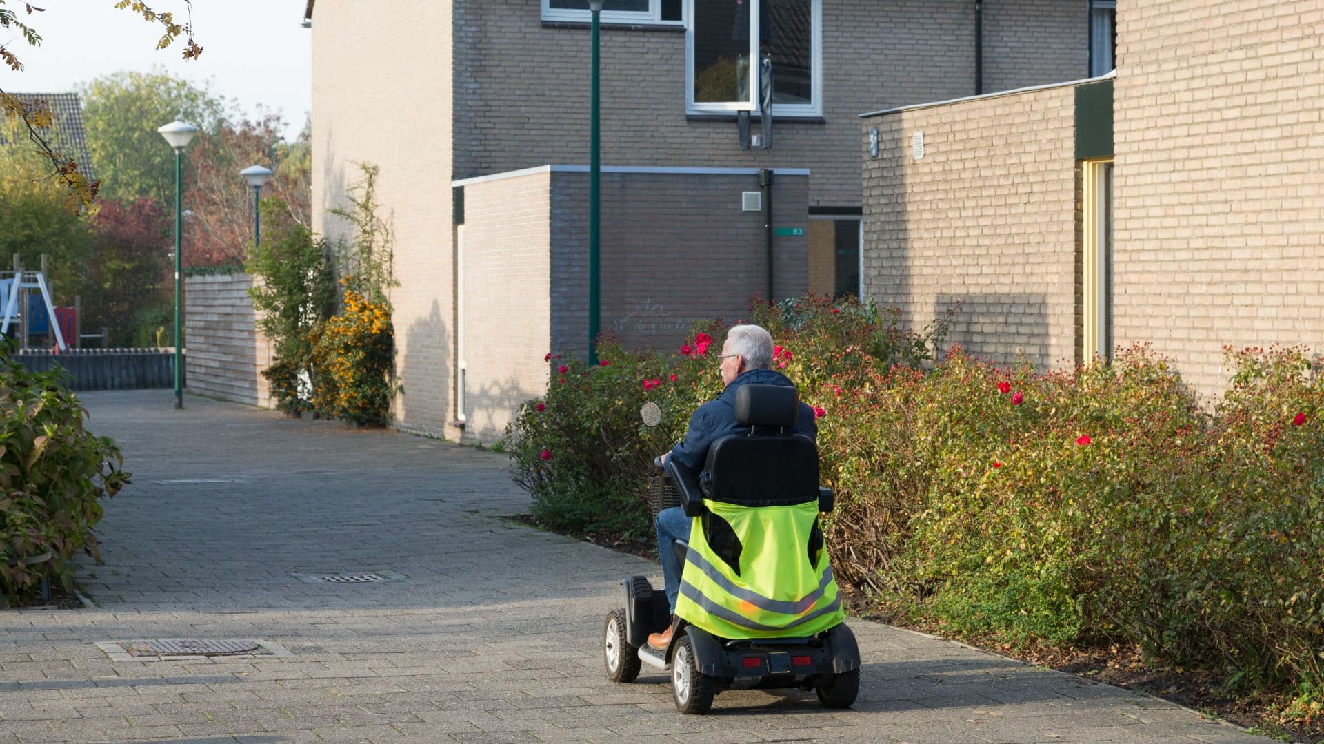 A rider in a hi-vis jacket on a mobility scooter in a residential street