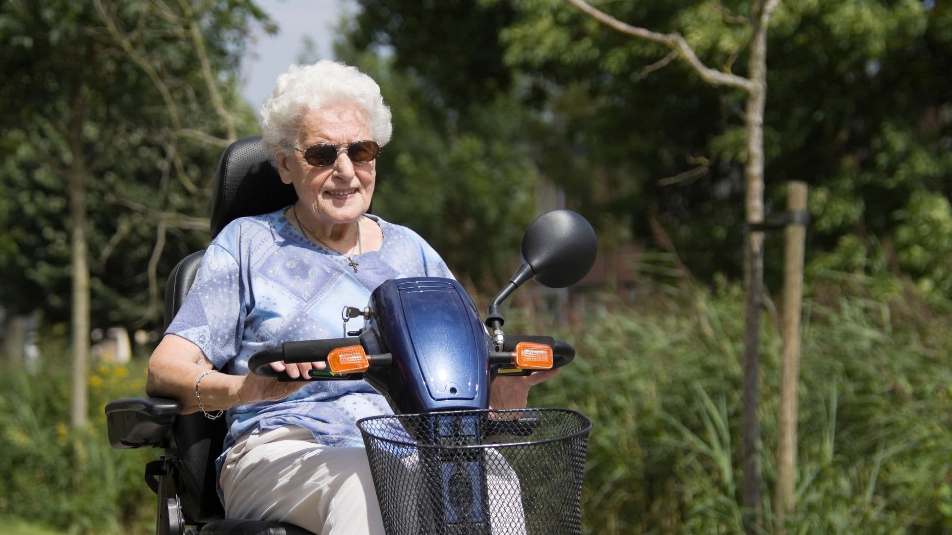 A woman on a mobility scooter on a tree-lined path