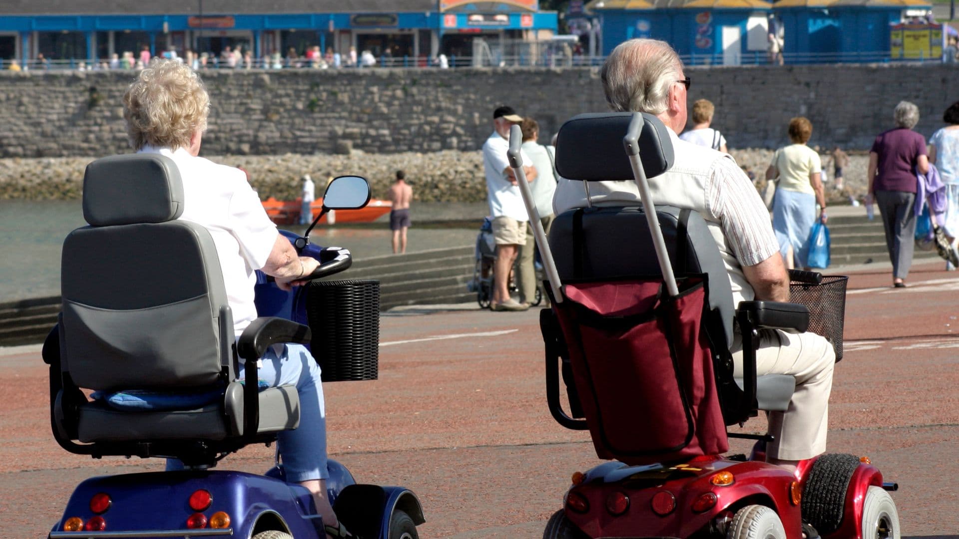 A person riding a mobility scooter along a seafront promenade